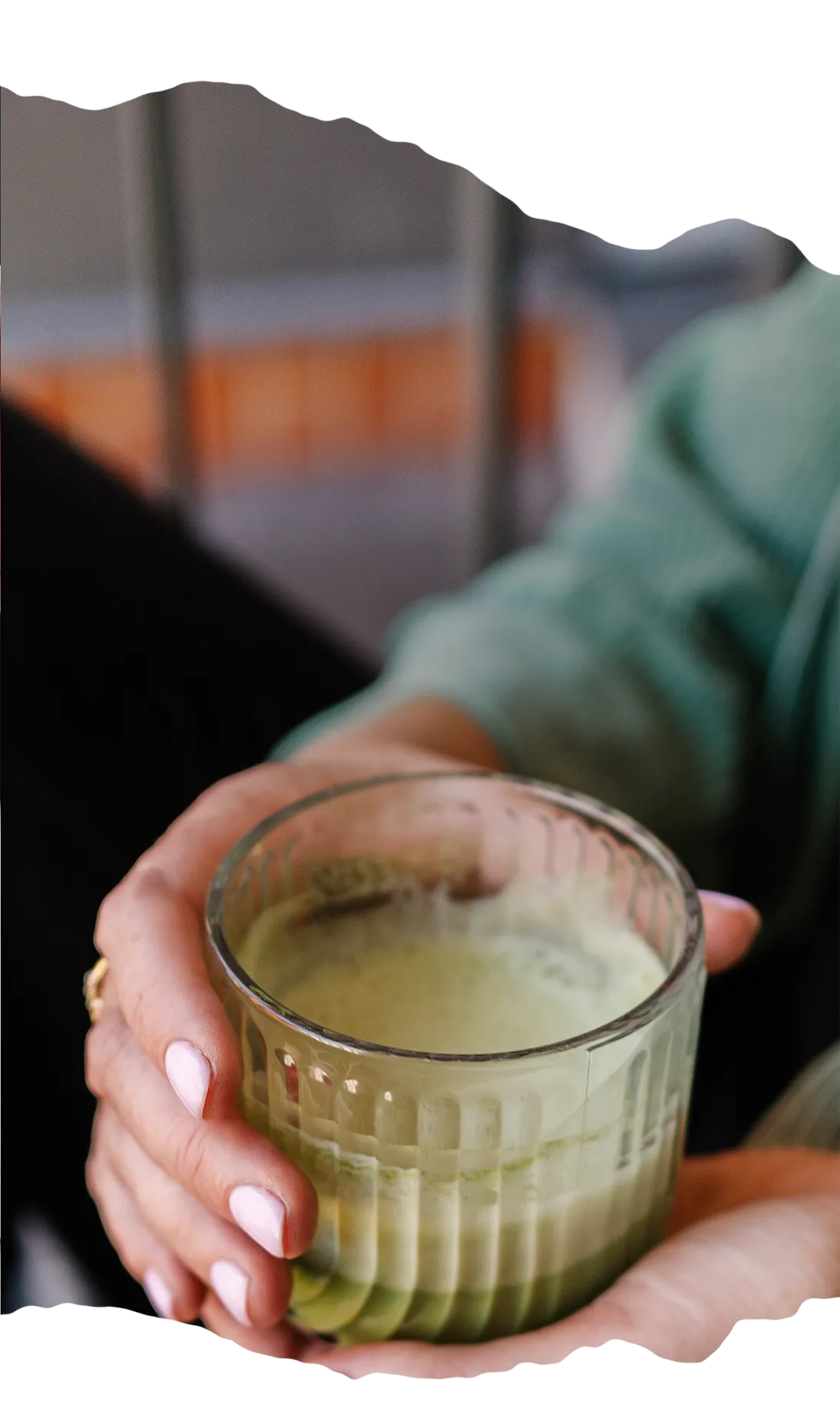 Dłonie trzymające szklankę matcha latte